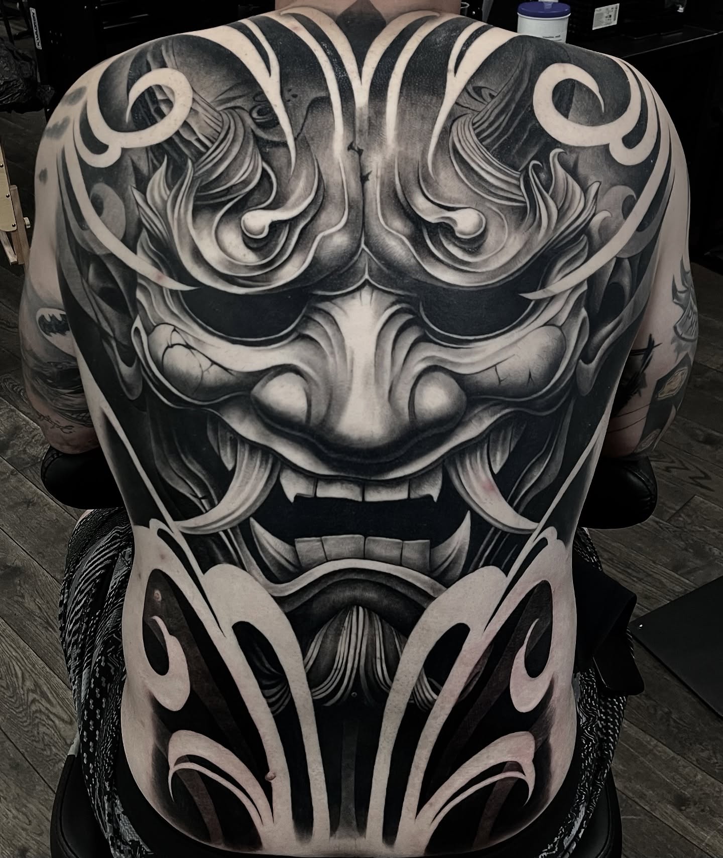 Blackwork tattoo full back piece covering the shoulders and spine in solid black ornamental work