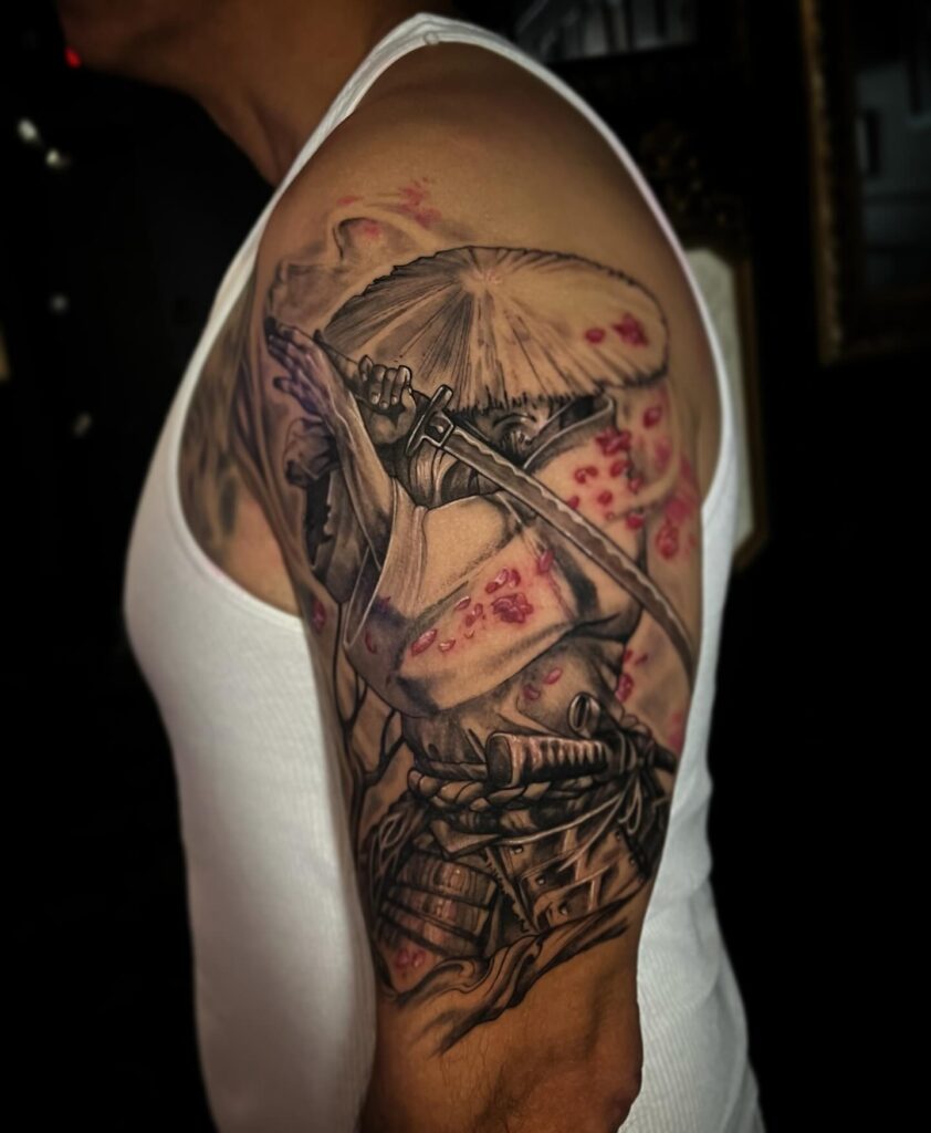 Samurai and cherry blossom colorful sleeve tattoo in red armour and soft pink petals.