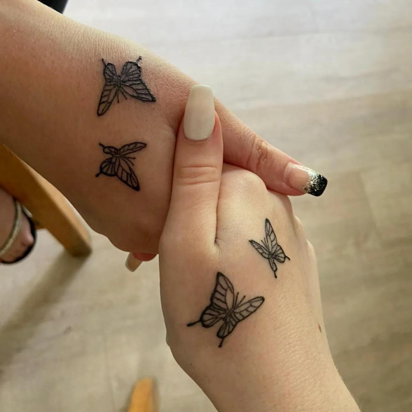 Sisters tattoo of two butterflies drawn as different species in matching line weight