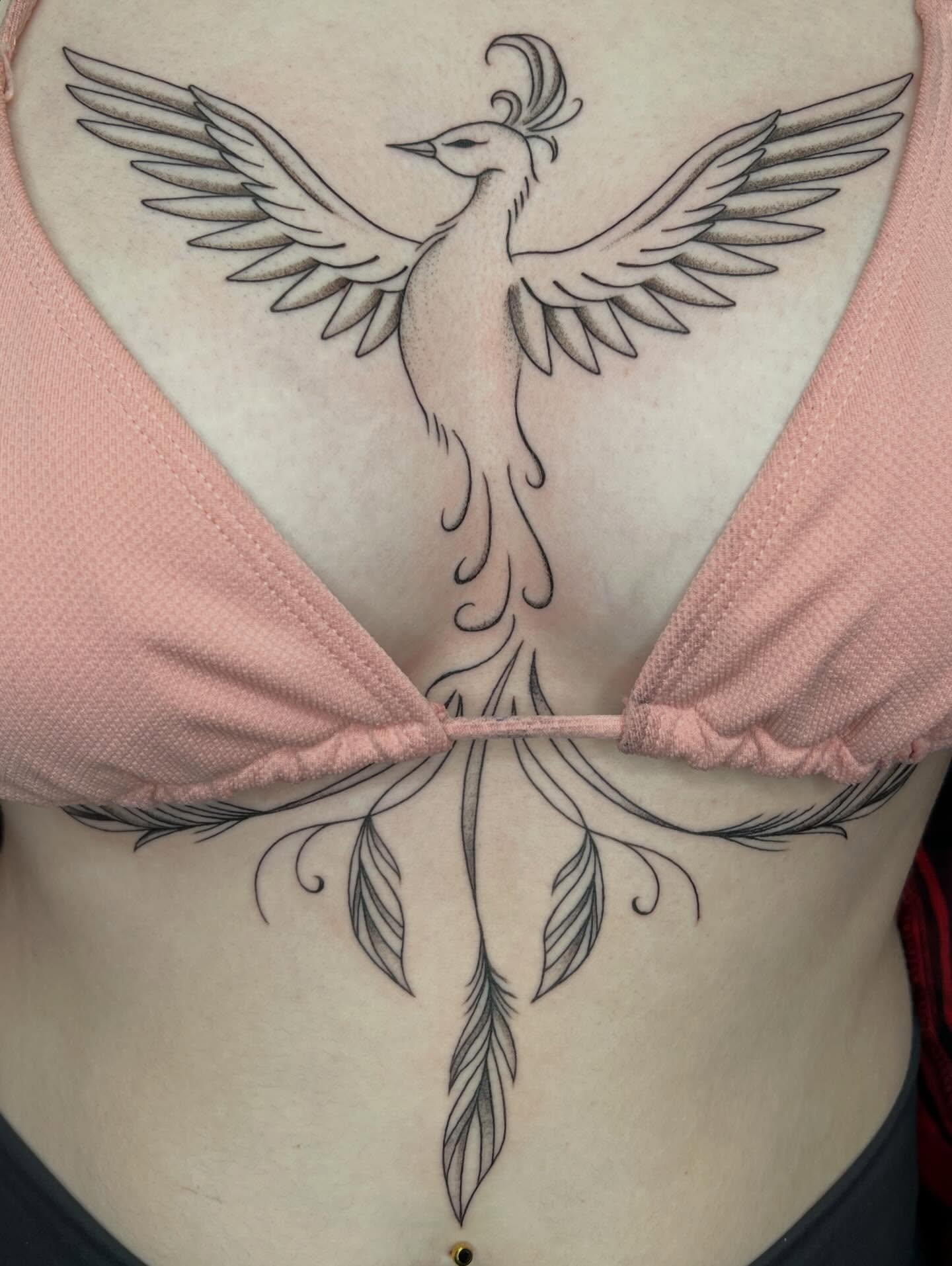 Phoenix sternum tattoo with sweeping wings spanning the underbust