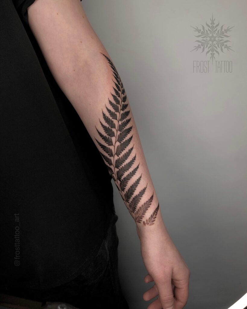 Blackwork fern tattoo with solid black fronds sitting in high contrast against bare skin