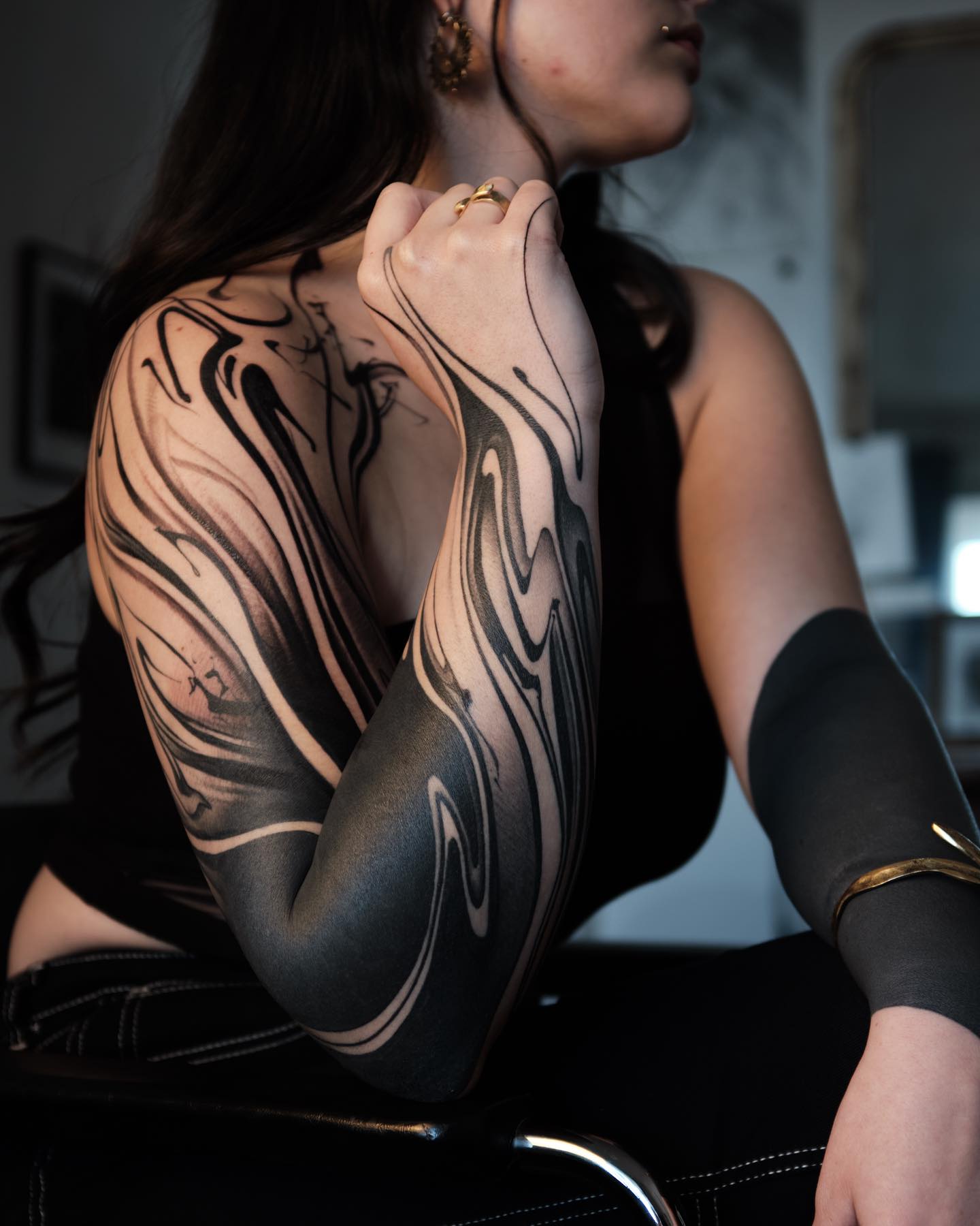 Abstract blackout tattoo on a woman's arm using large areas of solid black, a badass blackwork idea