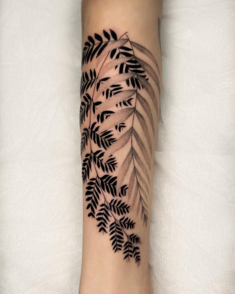 Tropical fern tattoo with broad split fronds rendered in bold black ink