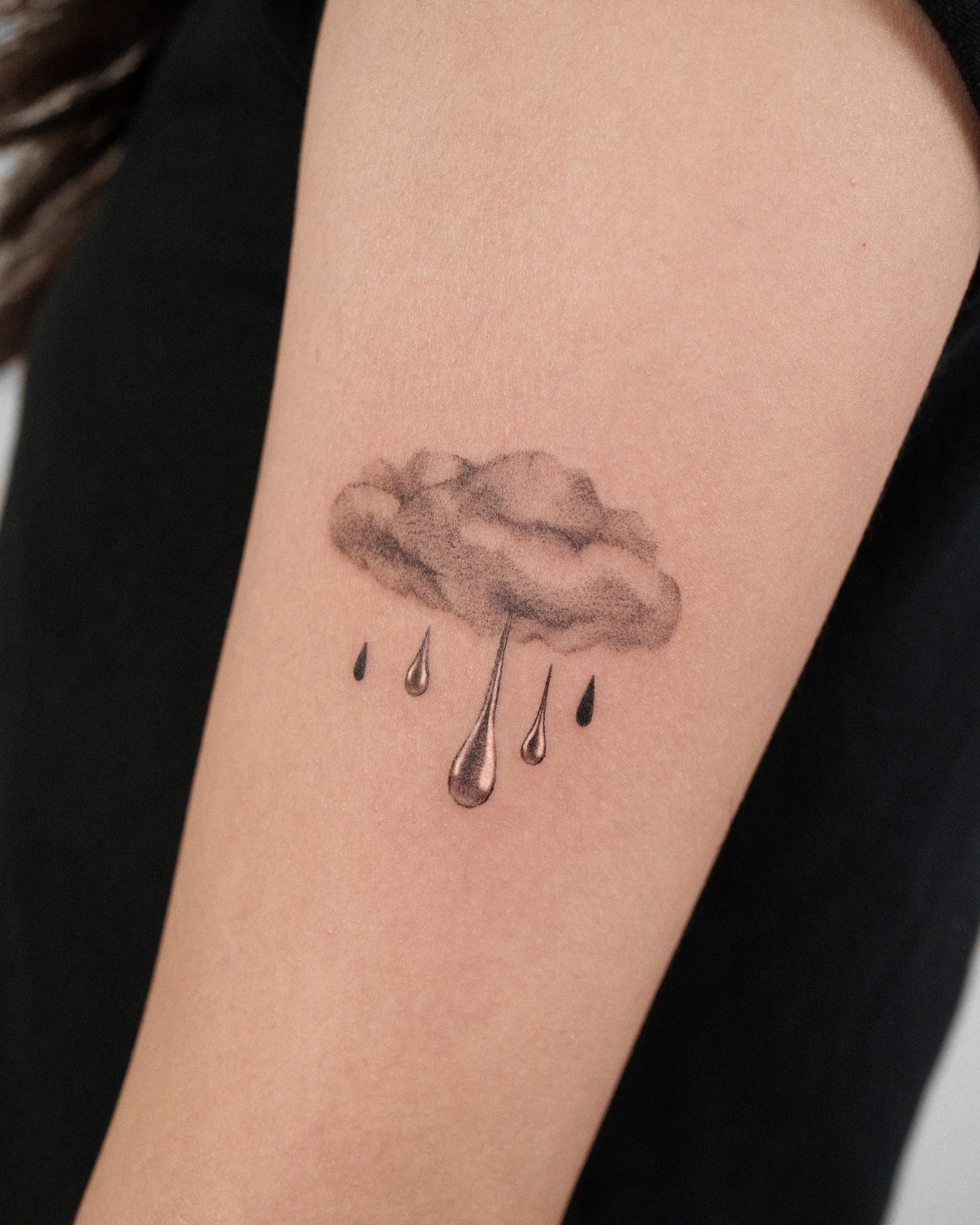 Small cloud tattoo in soft grey shading, one of the gentlest cute tattoo ideas for women.