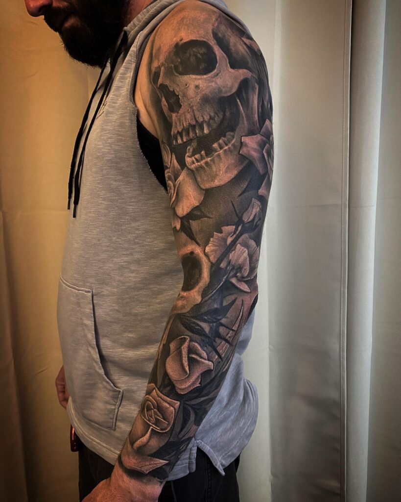 Rose and skull sleeve tattoo pairing memento mori imagery with full roses