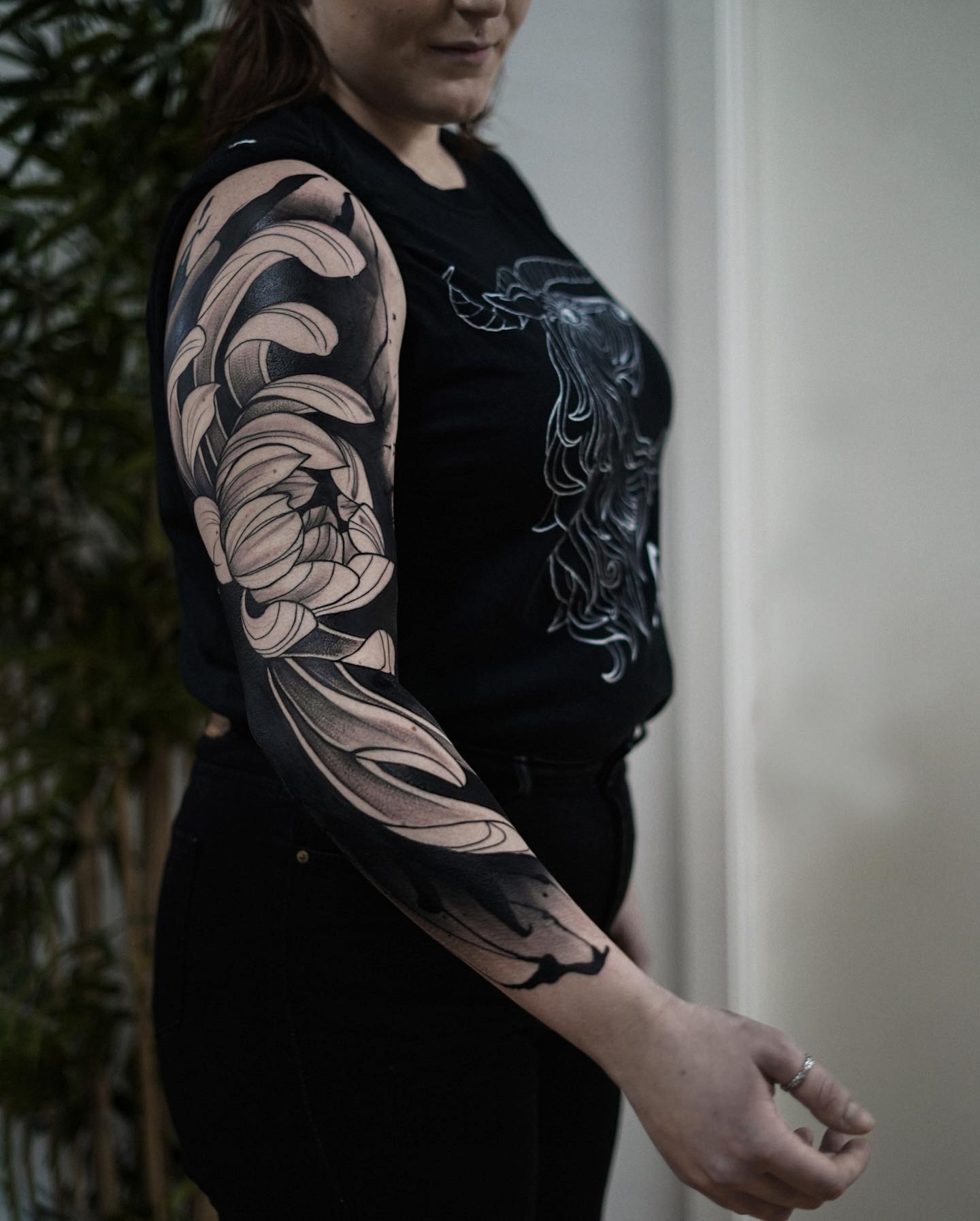 Negative space peony tattoo where the petals are formed from bare skin inside a solid black field