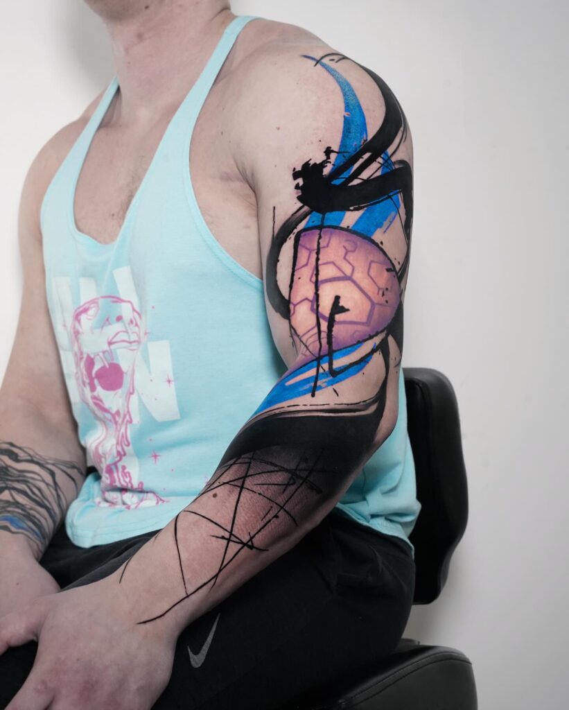 Watercolour abstract colorful sleeve tattoo with soft blue and magenta washes running down the arm.