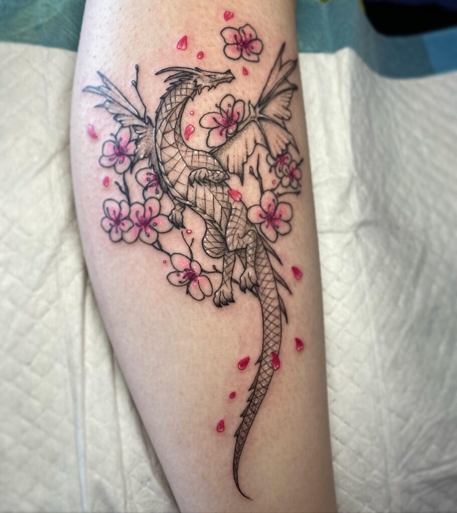 Dragon tattoo for women paired with cherry blossoms across the shoulder and arm