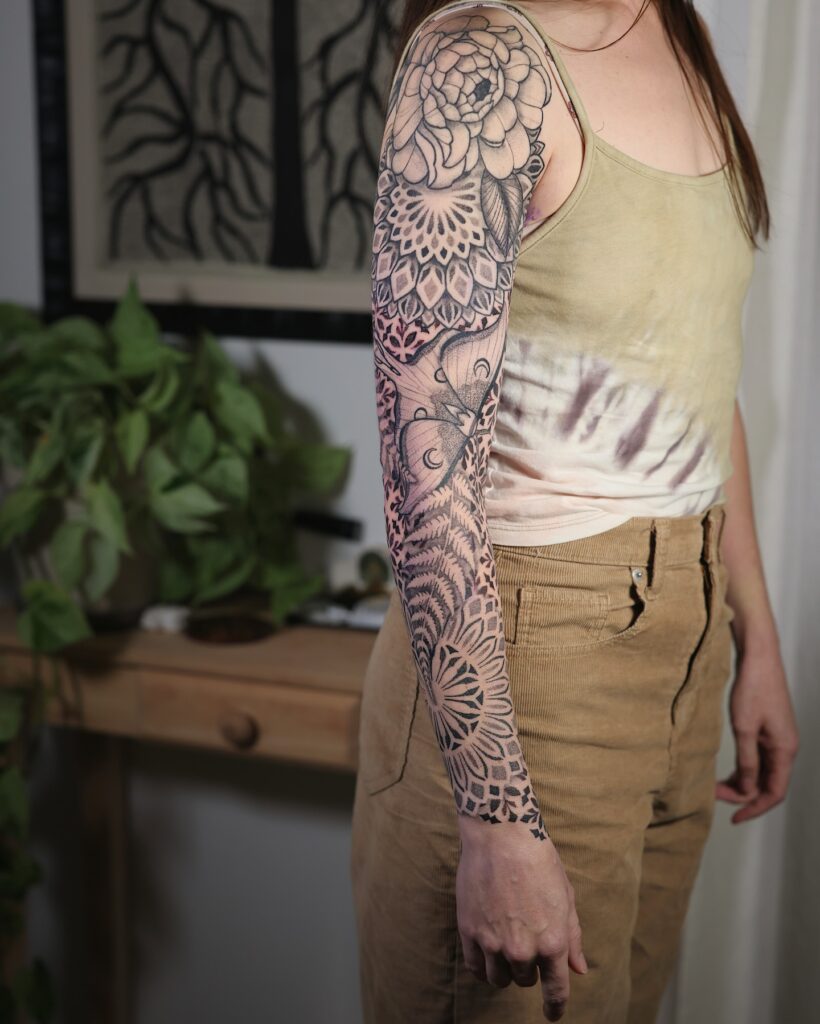 Fern tattoo used as connective greenery inside a botanical sleeve on the upper arm