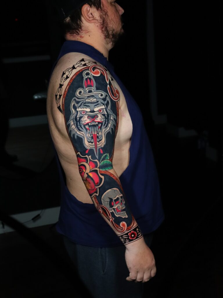 American traditional colorful sleeve tattoo built from bold red, green and gold panels.