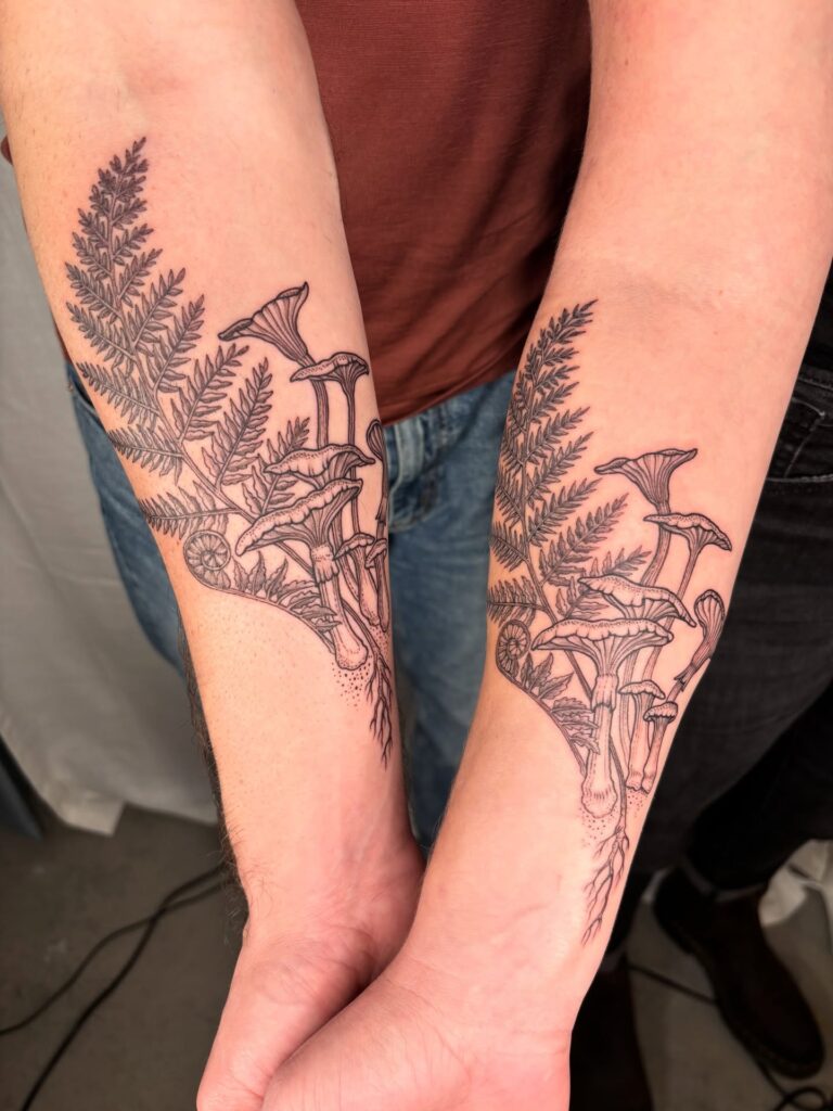 Fern and mushroom tattoo combining fronds with small toadstools at the forest floor