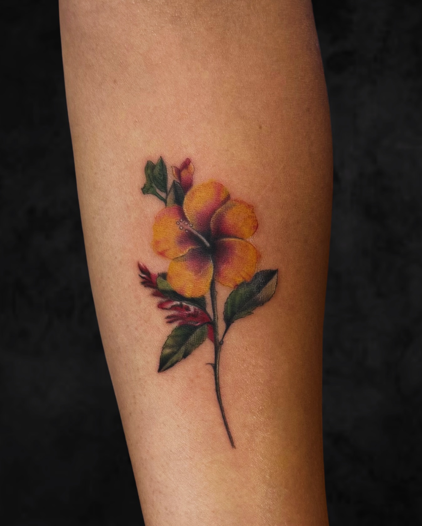 Yellow hibiscus tattoo on the arm, matching the pua aloalo Hawaii state flower