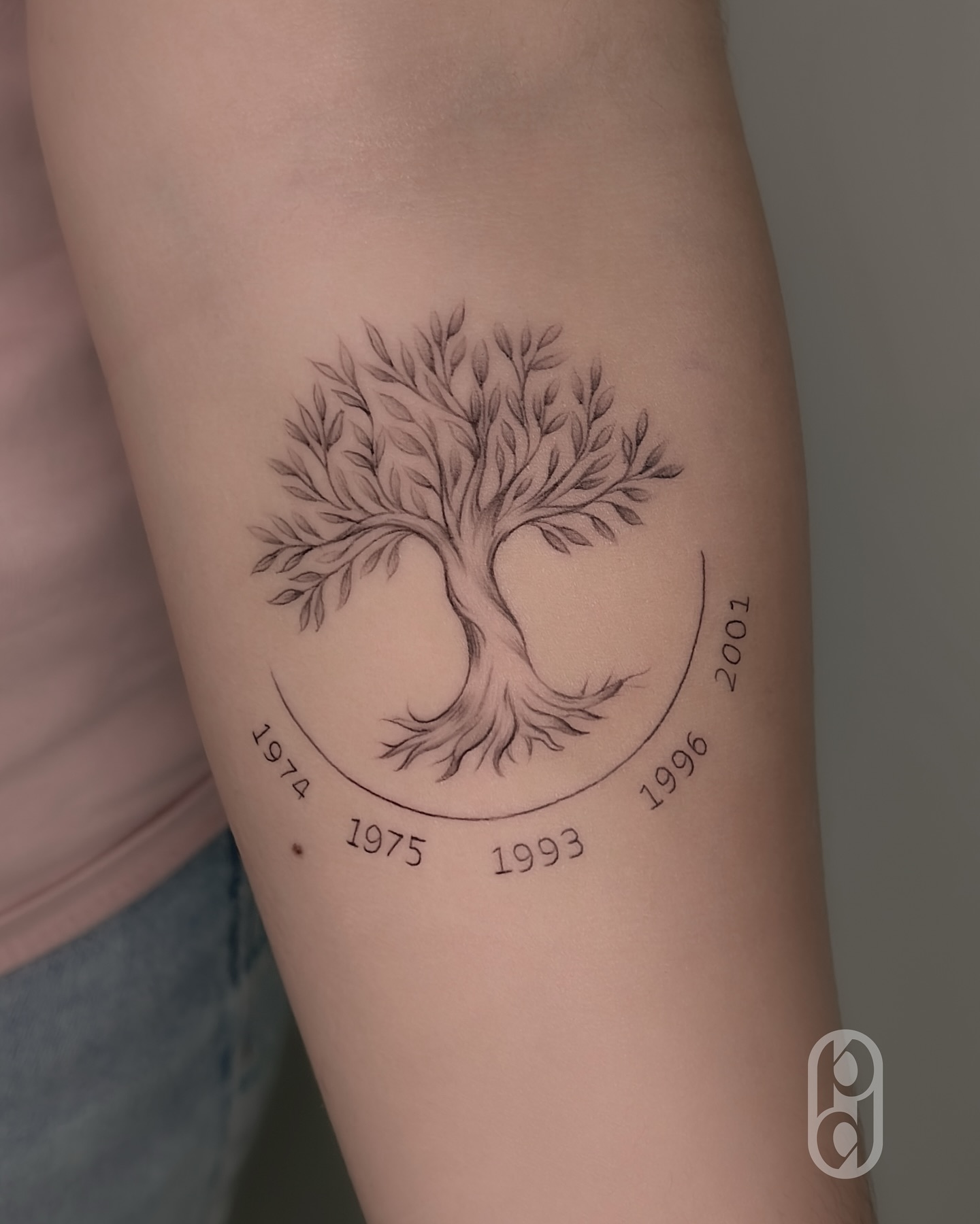 Family tattoo with two names joined by a fine-line heart on the forearm