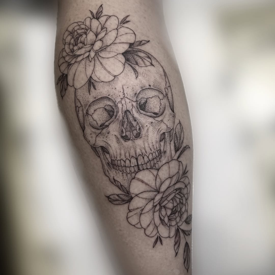 Feminine rose and skull tattoo with delicate roses framing a softly shaded skull