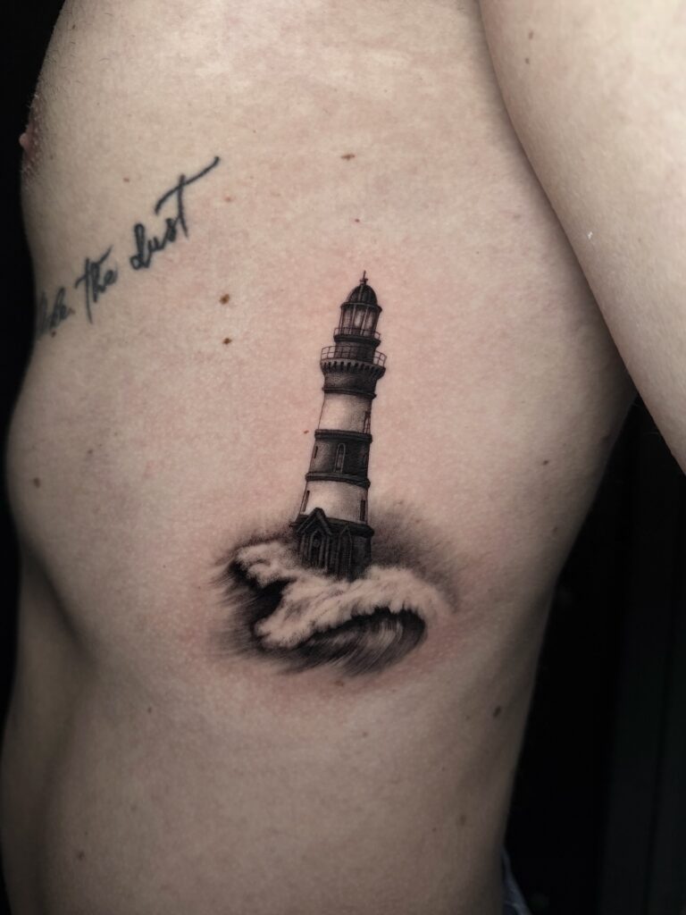 Small lighthouse tattoo for men in fine line detail, a meaningful symbol of guidance