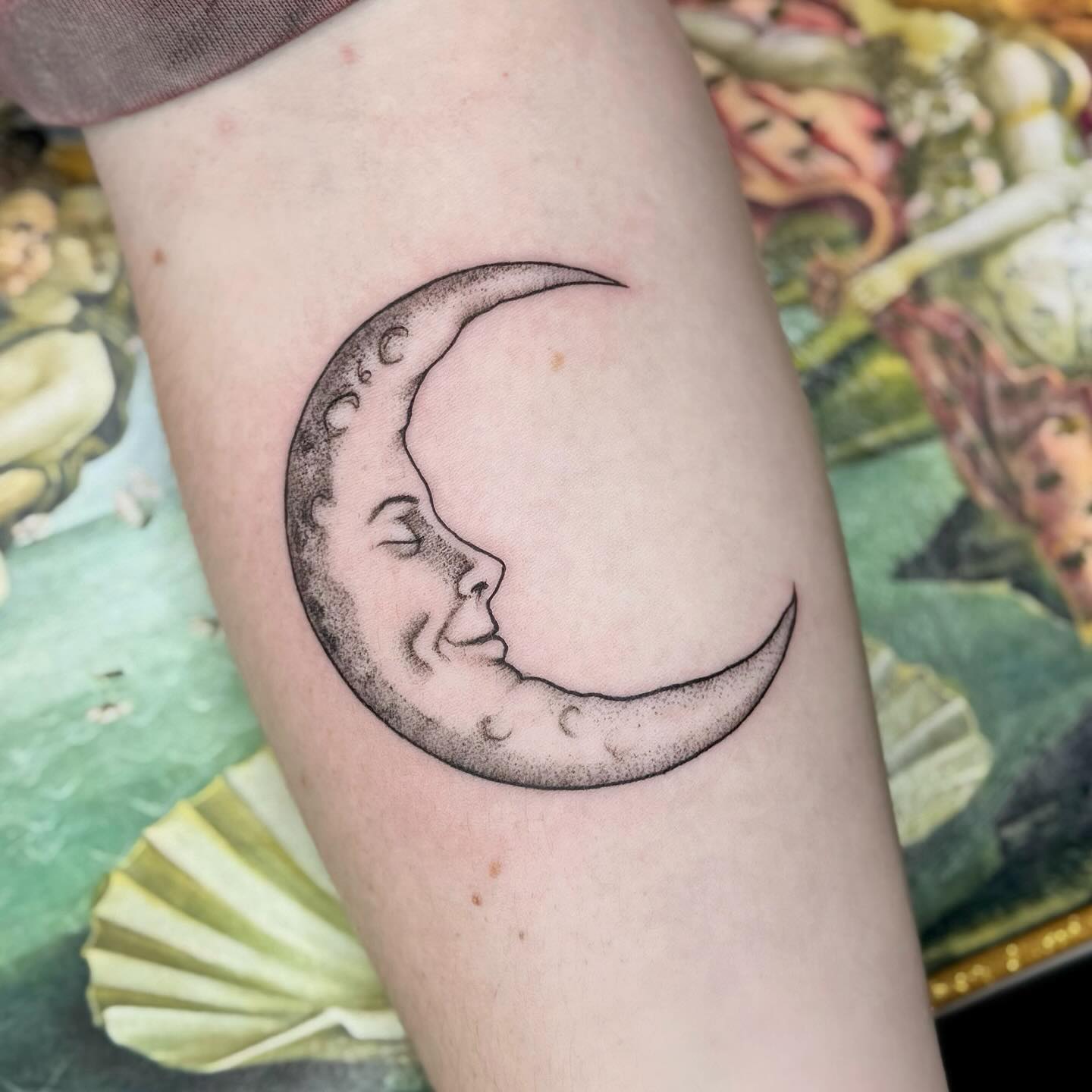 Celestial moon face tattoo with closed eyes and star detailing