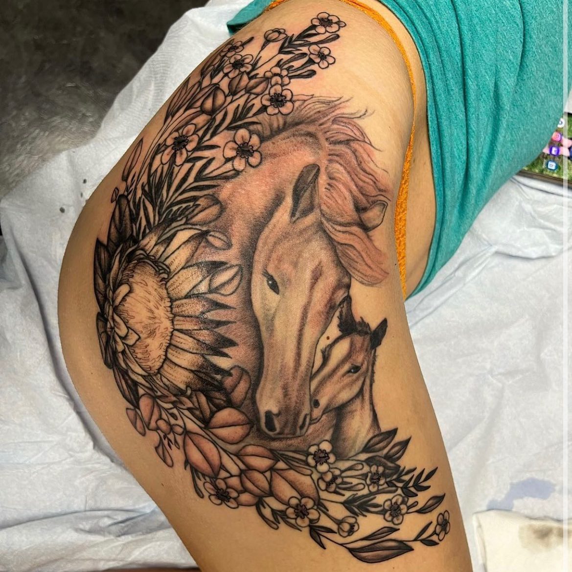 Horse tattoo surrounded by flowers, combining an equine head with botanical elements