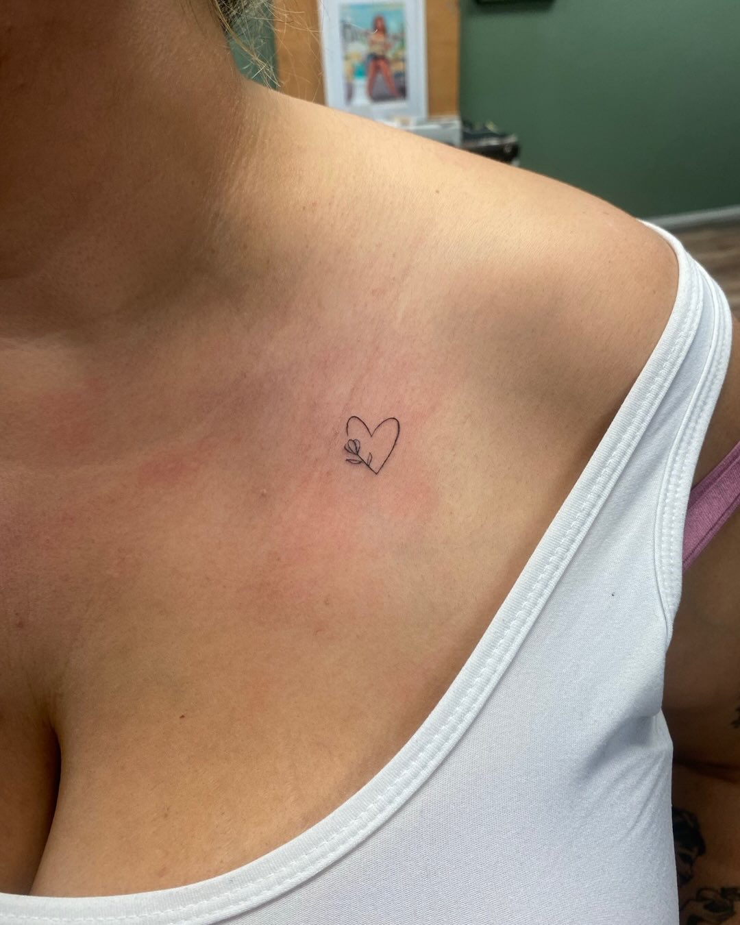 Micro tattoo of a tiny outlined heart in clean black linework.