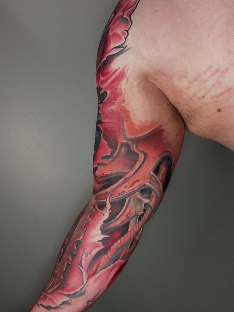 Biomechanical colorful sleeve tattoo with metallic teal and orange machinery under torn skin.