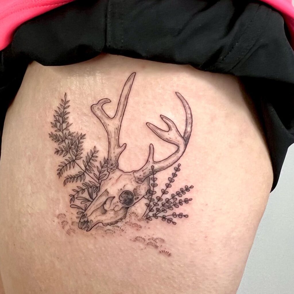 Fern and skull tattoo pairing botanical fronds with a small skull motif