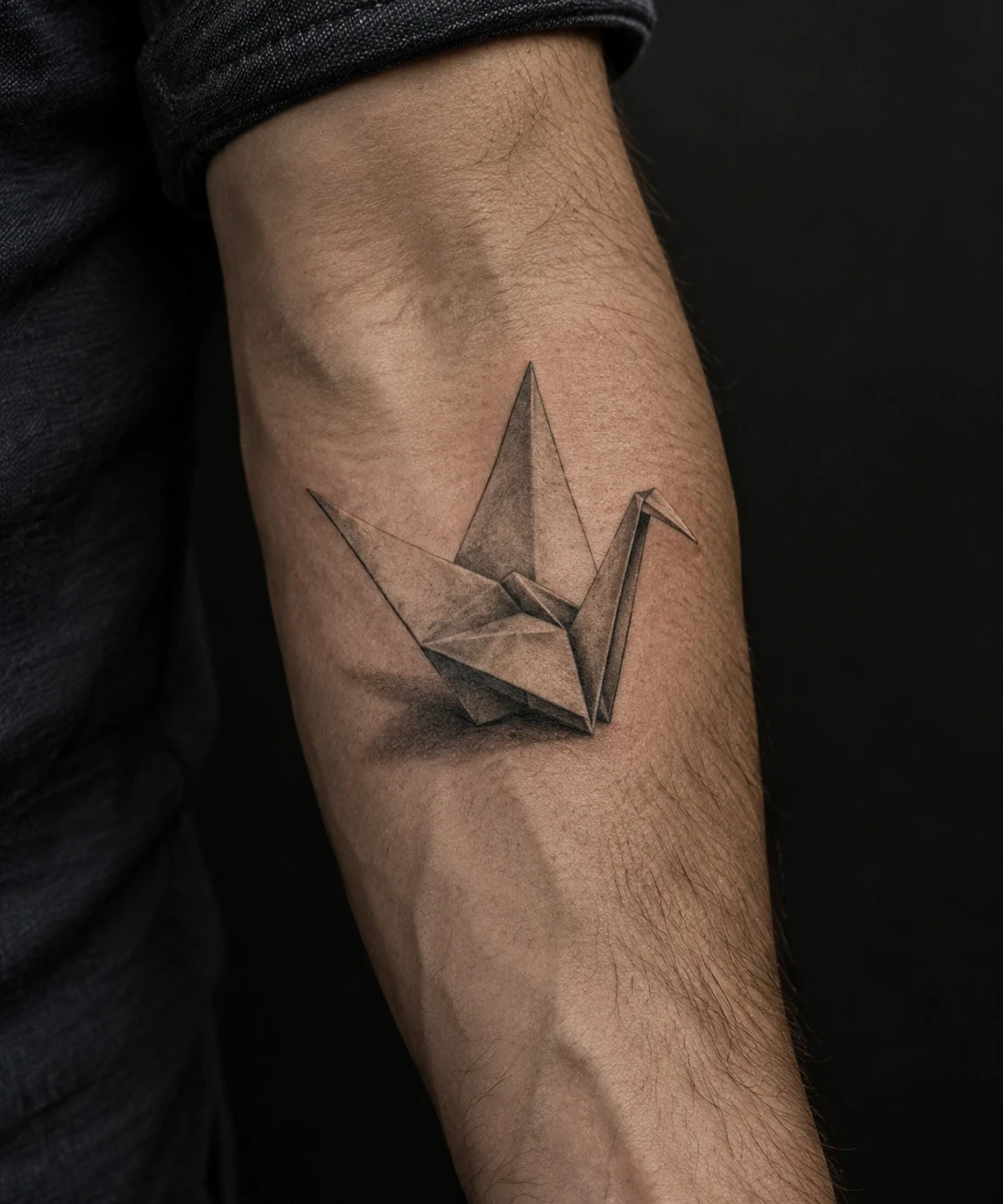 Origami crane tattoo with shaded paper folds and a cast shadow on a forearm