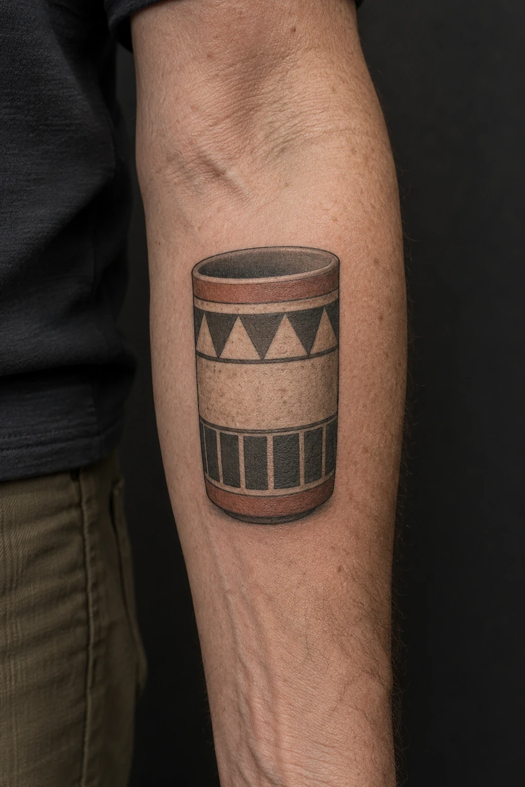 Cylindrical ceramic-vessel tattoo with terracotta geometric bands on a forearm