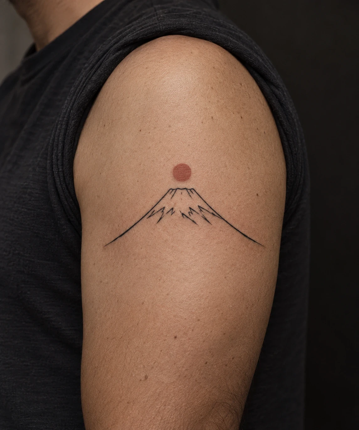 Mount Fuji-inspired outline tattoo with a snowcap and vermilion sun on an upper arm