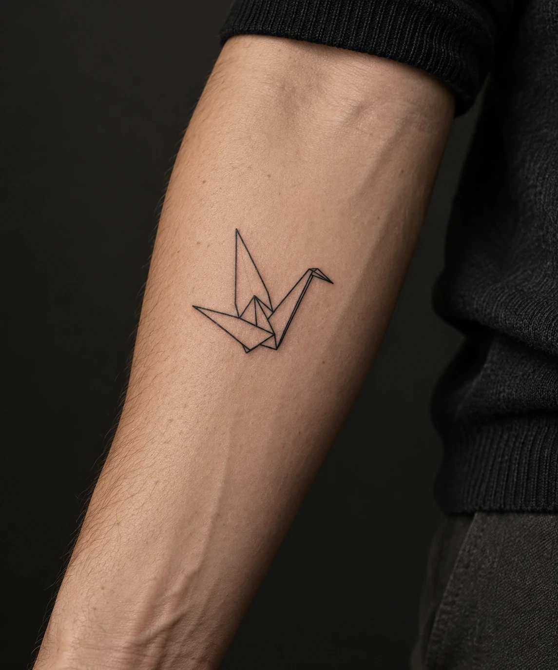 Outlined origami-crane tattoo with triangular wings on a forearm