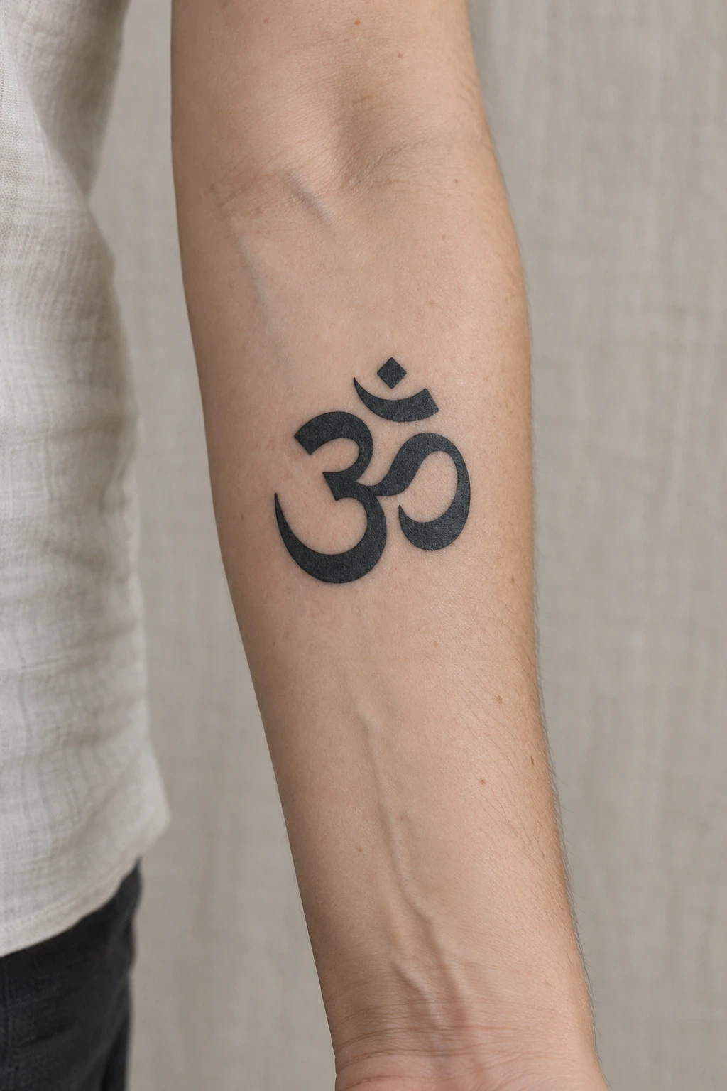 Bold black Om symbol tattoo on an inner forearm