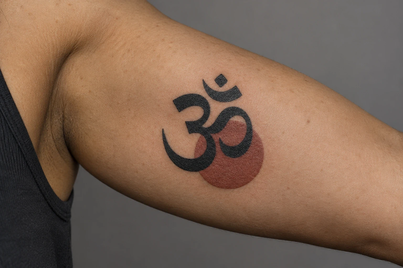 Black Om symbol with an offset brick-red disk on an inner upper arm